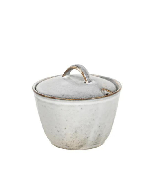 Introducing the SUGAR BOWL from Broste, this ceramic bowl features a matching lid with a charming curved handle. It showcases the Nordic Sand collection's rustic, speckled gray finish and slightly tapered shape, capturing Broste's signature coastal elegance.