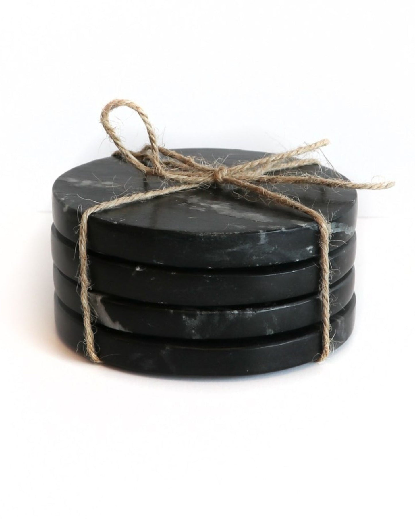 A set of four round, hand-carved MARBLE COASTERS by Hawthorne, elegantly tied with a jute twine bow. They are showcased against a plain white background, capturing the timeless elegance reminiscent of the Taj Mahal.