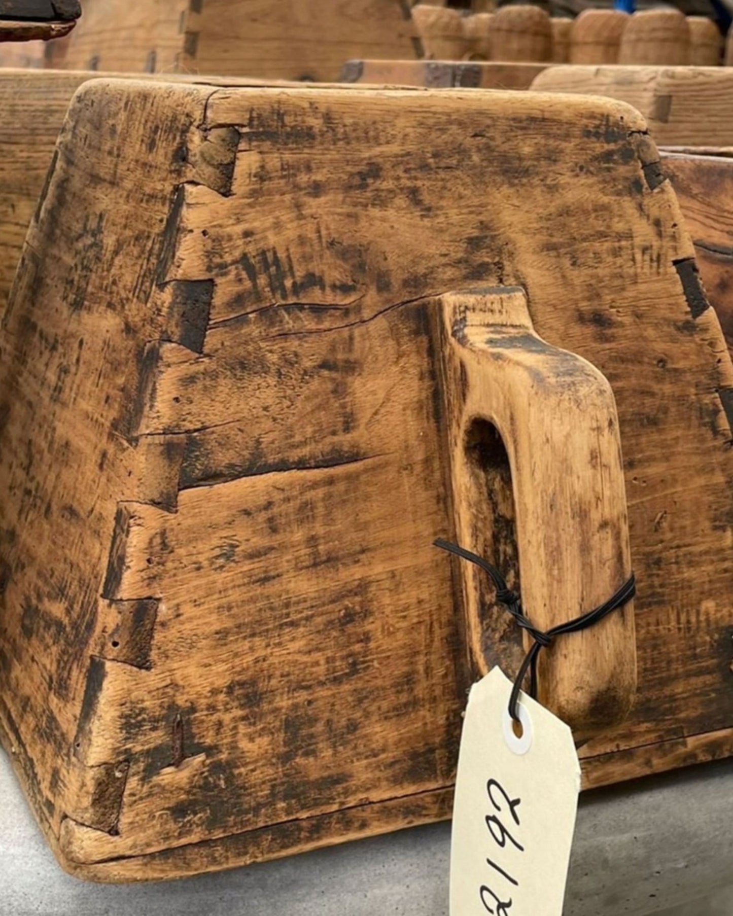 Close-up of Hawthorne's handcrafted ORIGINAL RICE MEASURE, a rustic wooden piece featuring dovetail joints and a handle, reminiscent of a large scoop or mold. A price tag marked 192 is attached to the handle. The wood reflects signs of age and wear, emphasizing the traditional techniques used in its creation.