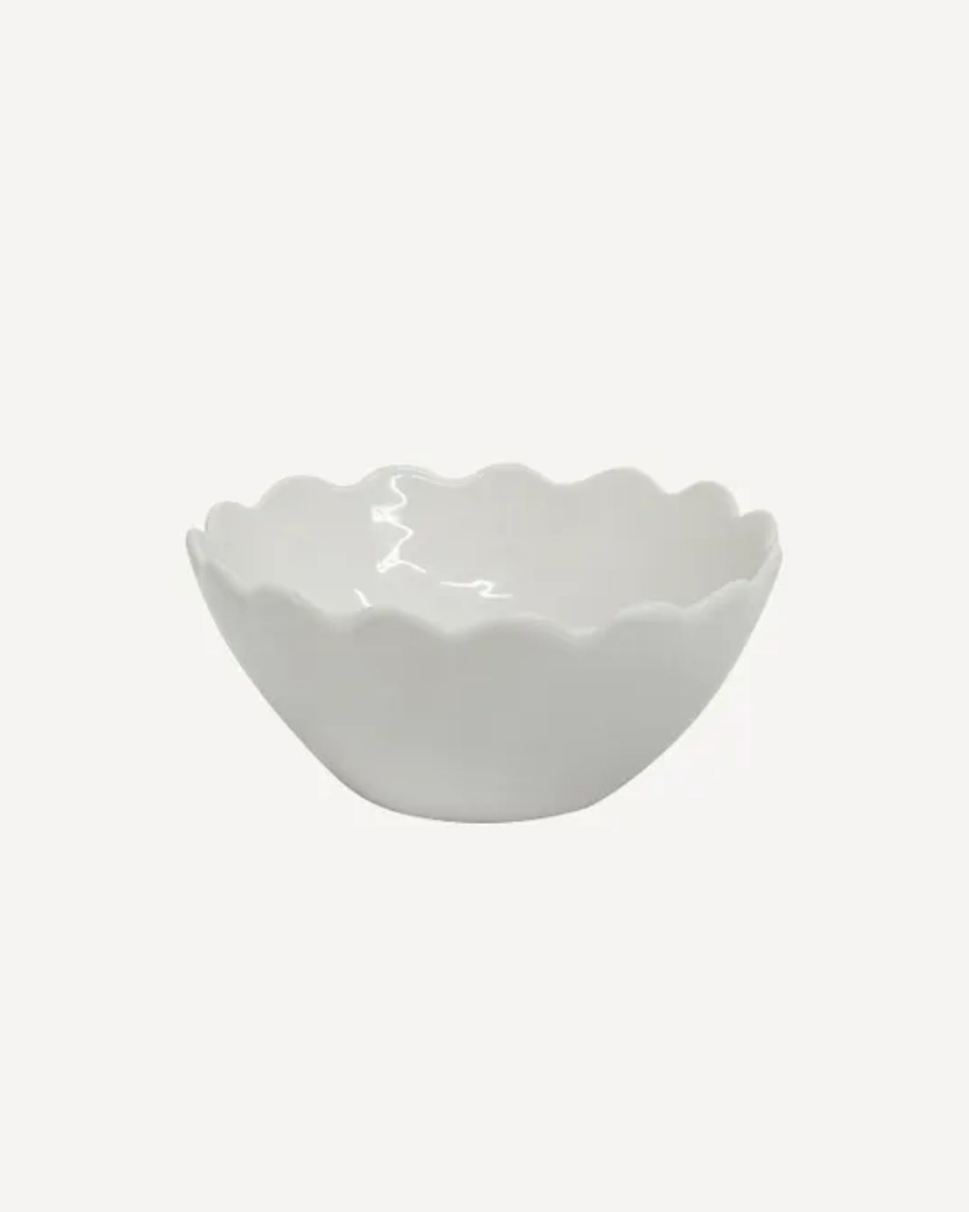 The PETAL CEREAL BOWL by French Country, showcasing an elegant petal design, gracefully sits on a plain light background, with its scalloped edge adding a touch of sophistication.