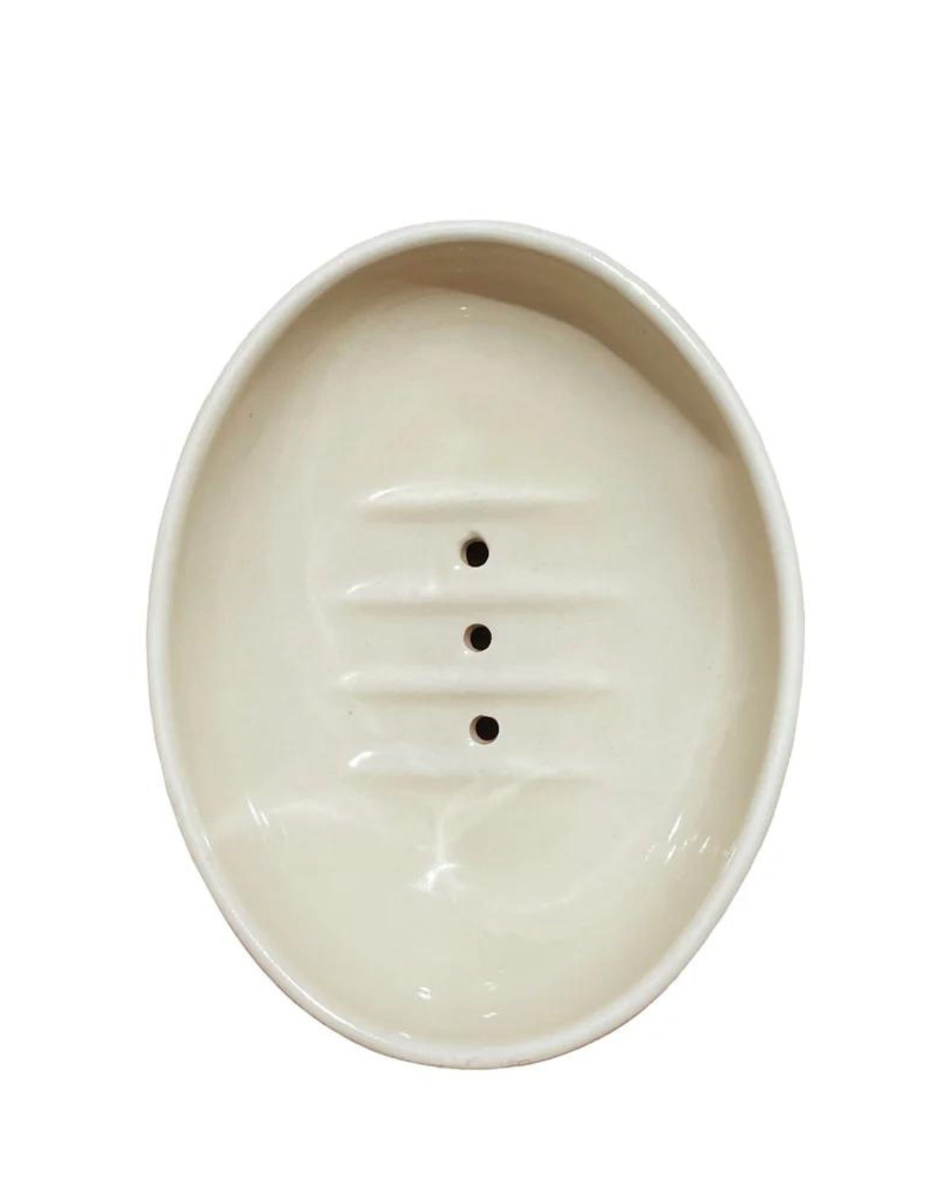 The Redecker OVAL CERAMIC SOAP DISH is an oval-shaped white ceramic soap dish featuring three drainage holes in the center, inspired by Bunzlauer ceramic design.