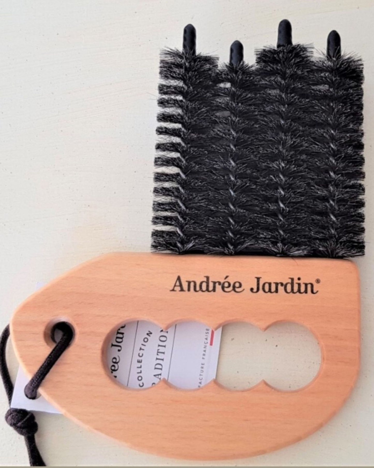 Introducing the Andree Jardin WINDOW BLIND/SHUTTER BRUSH, a wooden handheld brush crafted with three rows of dense black bristles for effective cleaning. Ideal for window blinds and shutters, it boasts a rounded handle with finger grips and a convenient string for easy hanging.