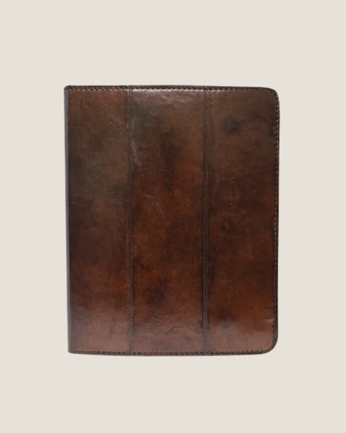 The LEATHER IPAD CASE brown leather binder featuring a smooth, polished finish and exposed stitching along the edges.