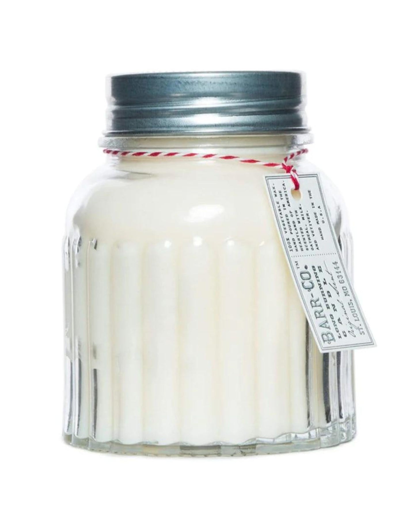The BARR CO ORIGINAL 120HR APOTHECARY CANDLE by Barr Co is housed in a glass jar with a silver metal lid, featuring vertical ribbed detailing. It includes a vintage-style label attached with a red and white string, and is crafted from soy wax.