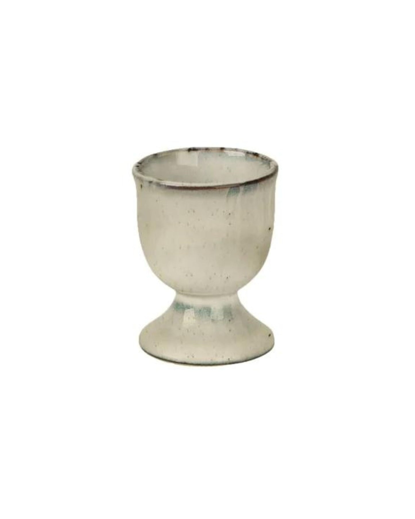 A small ceramic egg cup from Broste, in a white hue, elegantly adorns the breakfast table. Its design includes a wide base and rounded top, with subtle speckles that enhance its slightly weathered charm.