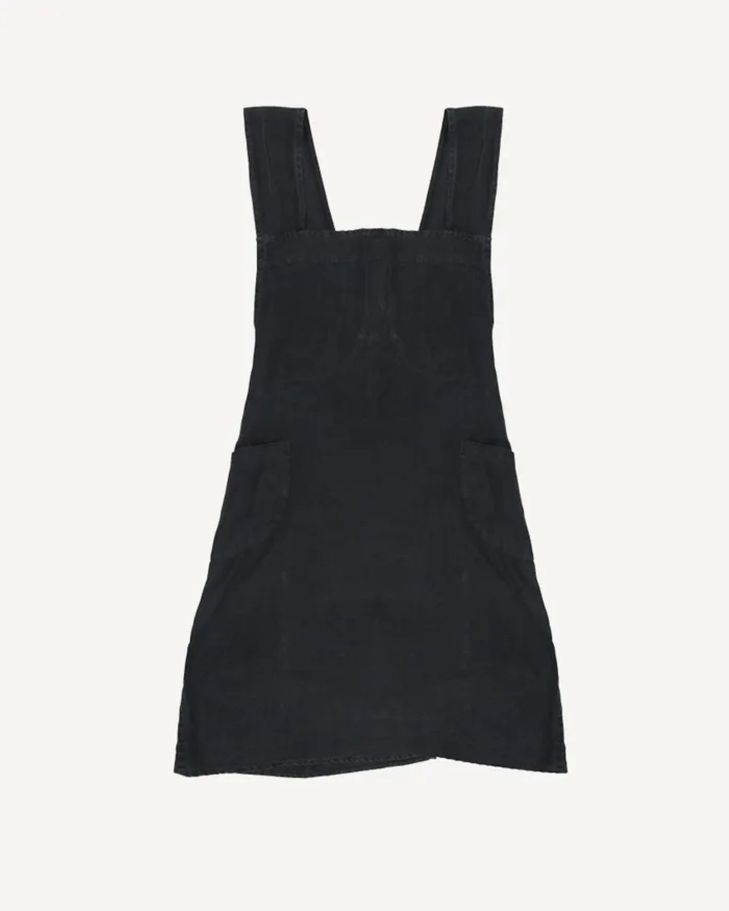 The CROSS BACK APRON STONEWASHED LINEN by French Country, featuring a stonewashed black design with wide shoulder straps and two large front pockets, reminiscent of a stylish pinafore dress, is laid flat on a plain white background.
