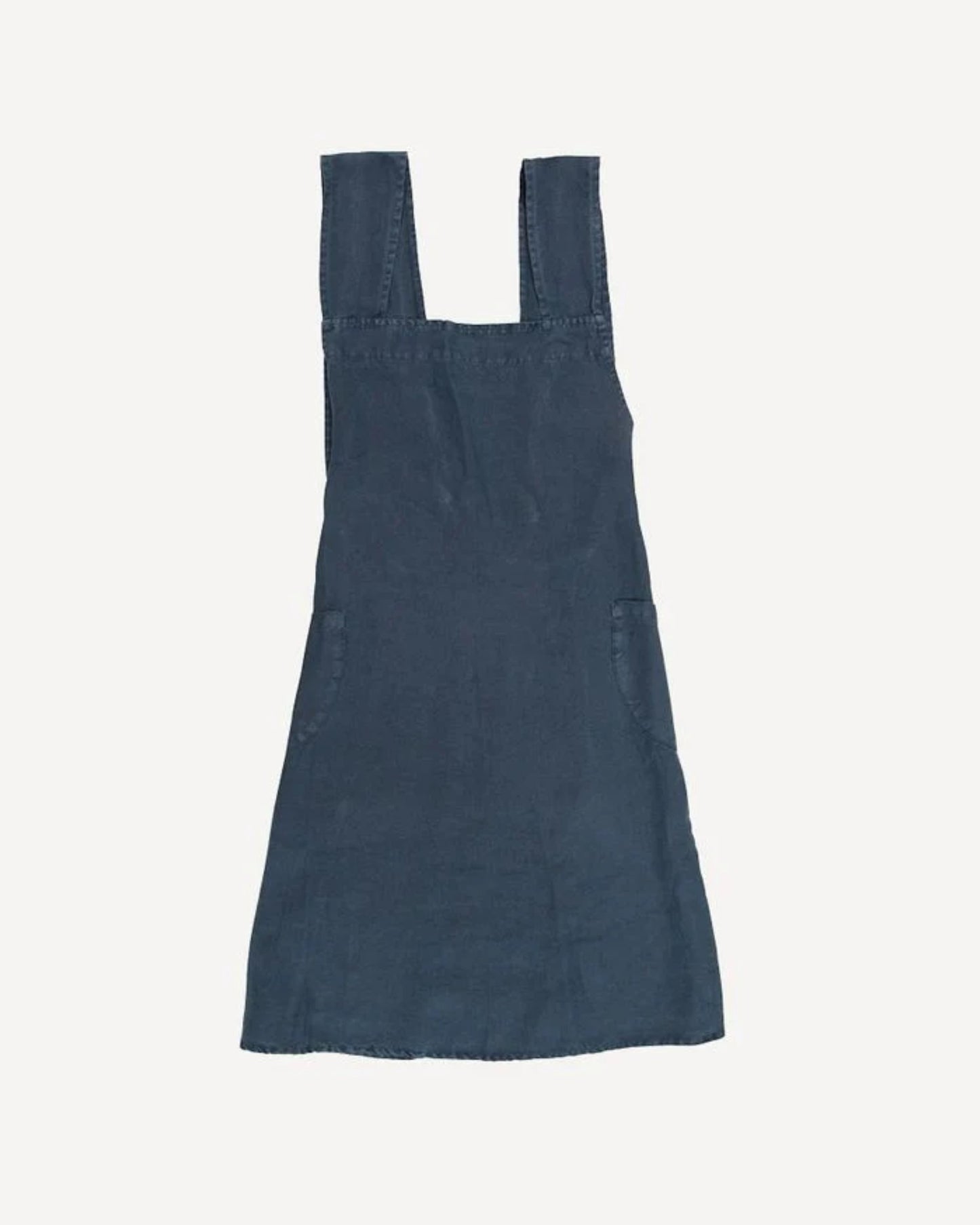 A stonewashed black linen cross-back apron by French Country, featuring wide shoulder straps and large pockets on the sides, laid flat against a plain off-white background.