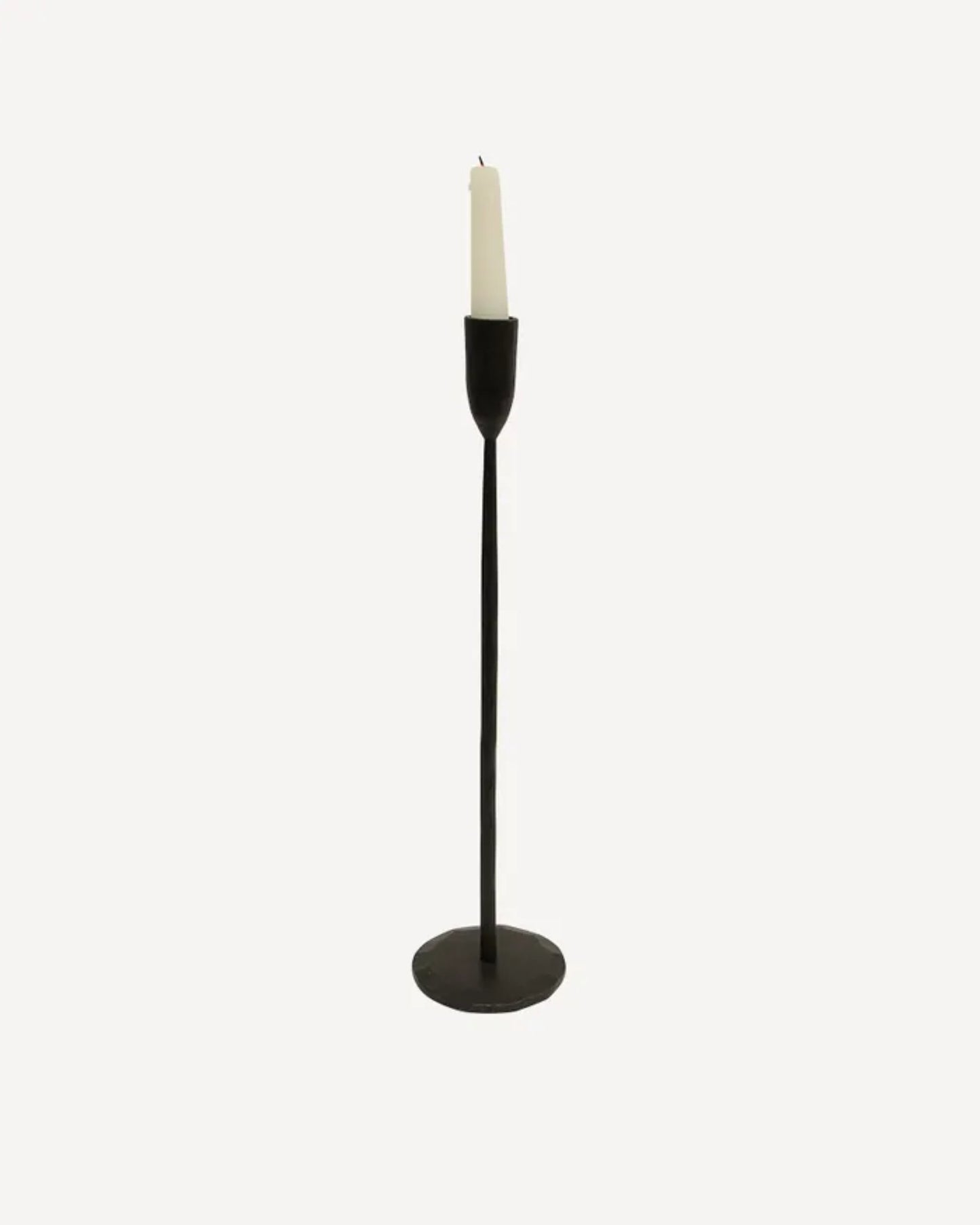 The DAX CANDLEHOLDER- BLACK by French Country, a hand-forged matte black metal candle holder with a wide base, cradles a single white candle against a plain white background.
