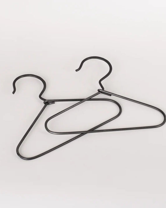 Two MINI BURNISHED COAT HANGERS from New Direction overlap against a plain white background. Their minimalist design features hooks at the top, and they are positioned at different angles, creating an aesthetic that exudes both elegance and simplicity.