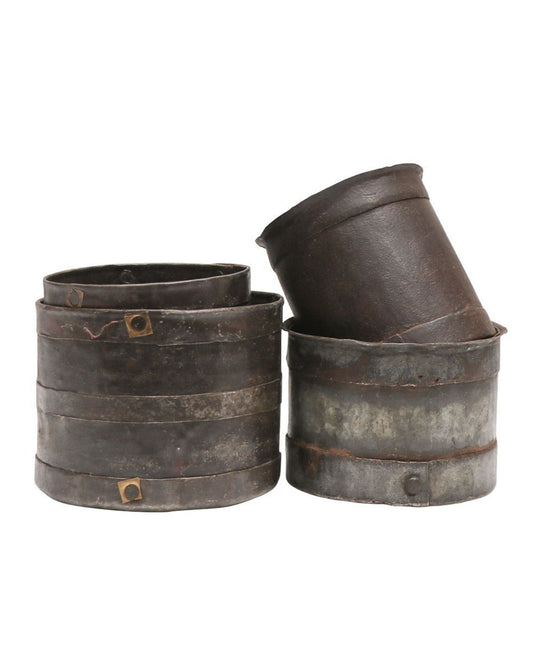 A collection of four ORIGINAL IRON MEASURING POTS by Hawthorne features vintage, weathered metal tins with rounded edges that reflect traditional craftsmanship. Three pots are neatly stacked and one is tilted on top, highlighting the charm of their rust and wear against a plain white background.