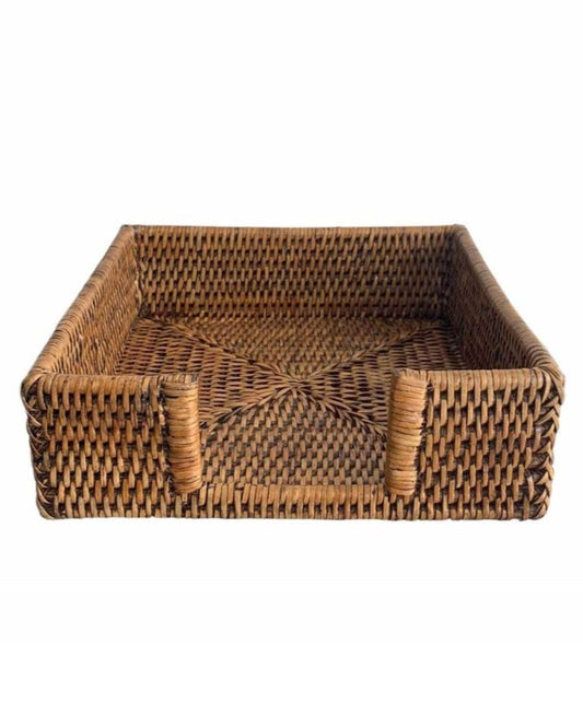 Introducing the RATTAN NAPKIN HOLDER by Le Monde: a square, woven wicker tray that exudes rustic elegance with its raised sides and brown finish. Designed with two handles for easy carrying and featuring a tightly interlaced pattern, this eco-friendly rattan piece ensures both sturdiness and style.