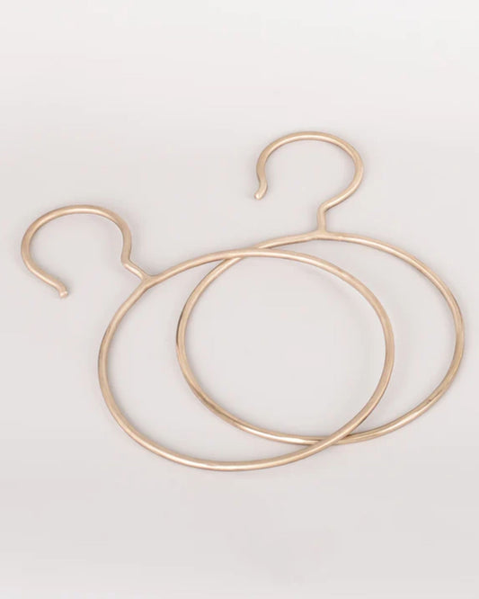 Product: Two gold-colored, circular metal items from New Direction's SOLID BRASS SCARF DISPLAY collection are positioned on a plain white background. These handmade pieces showcase a closed circle with one end curving outward like a hook, making them both stylish and functional accessories.