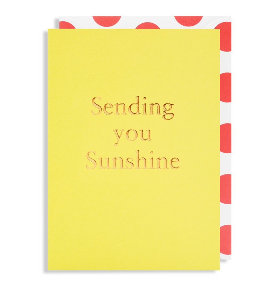 A vibrant yellow SENDING YOU SUNSHINE - GREETING CARD by Oxted, beautifully gold-embossed, graces the scene, accompanied by an envelope with a striking red polka dot interior.