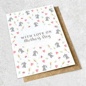 The WITH LOVE ON MOTHER'S DAY - GREETING CARD by Ink Bomb features the text "WITH LOVE ON Mothers Day" along with small illustrations of hearts, flowers, and teapots. The card is shown resting atop a brown envelope on a gray surface.