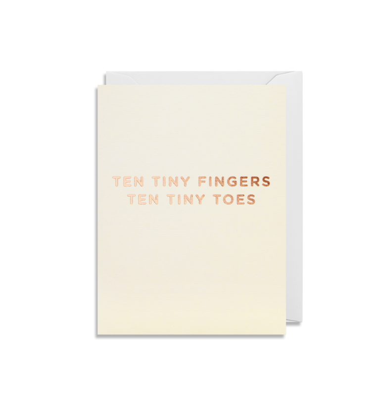 A minimalist greeting card from Oxted, titled "TEN TINY FINGERS TEN TINY TOES - GREETING CARD," features metallic rose gold text on a cream background.