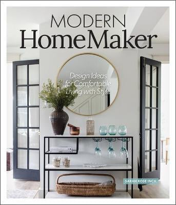 The cover of the "MODERN HOME MAKER" book, authored by Sarah Rose Inch and published by Nation Wide Books, features a chic interior setting. A round mirror, elegant vases, and glassware adorn a console table set against a pristine white wall. The arrangement is framed by black-framed glass doors. The text highlights "Design Ideas for Comfortable Living with Style," making it an ideal resource for home décor inspiration.