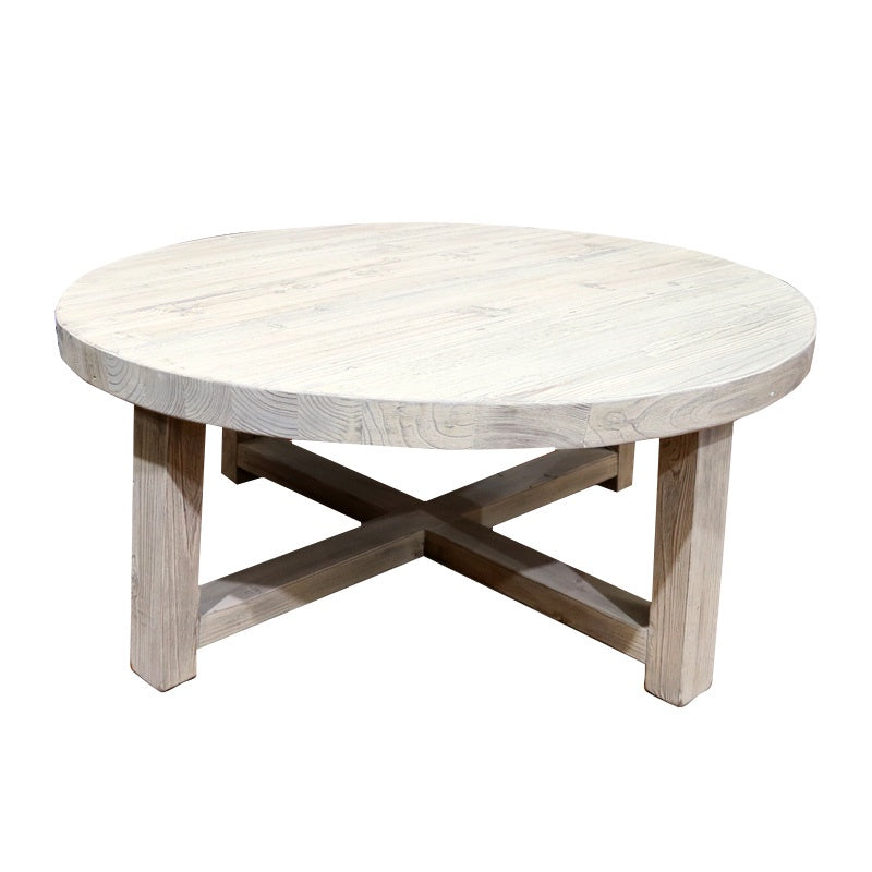 The RUSSELL COFFEE TABLE by Le Forge is a minimalist light wooden round coffee table crafted from reclaimed pine. It boasts a smooth tabletop and sturdy legs connected by an X-shaped support structure, capturing coastal-inspired elegance.