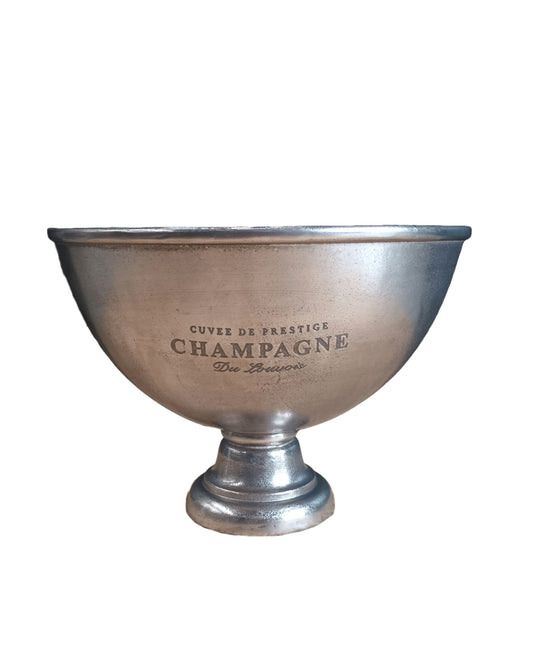 A large champagne bucket from Artwood, made of antique nickel and engraved with "Cuvee de Prestige Champagne," stands elegantly on a short pedestal base. This silver piece is essential for hosting.