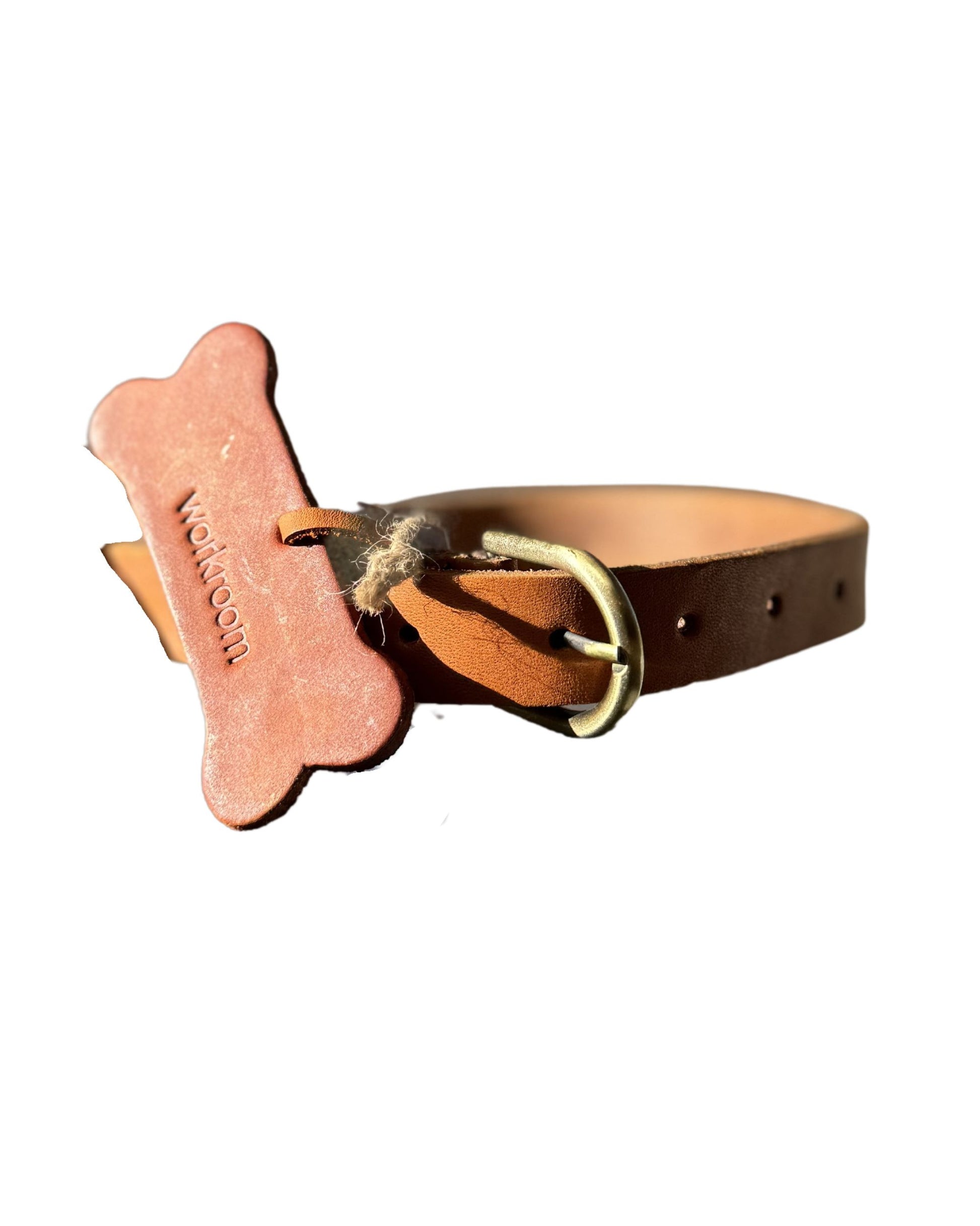 The Workroom's FLAT DOG COLLARS are crafted from premium leather and come adorned with a bone-shaped tag that reads "WOOF WOOF," designed to resemble a dog biscuit. These collars feature a gold buckle, multiple adjustment holes, and robust hardware for lasting durability.