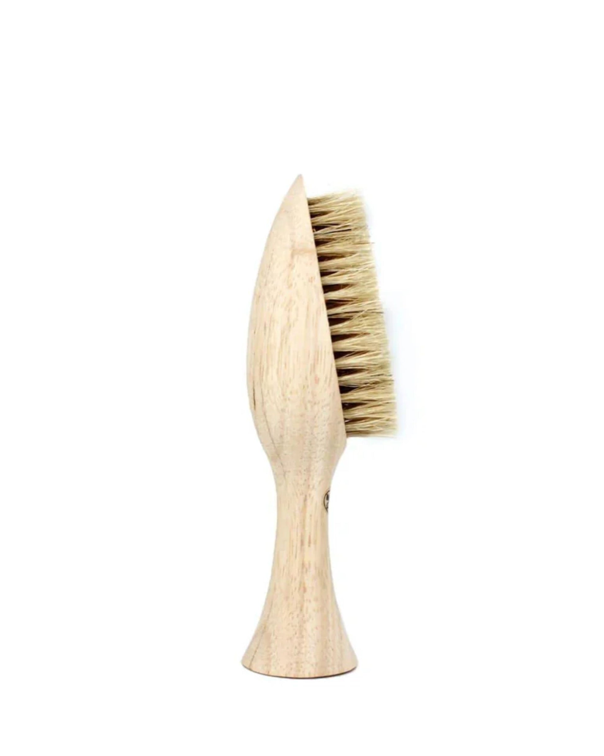 The Saison SANTORINI NAIL BRUSH boasts a wooden handle and a distinctive, contoured design. Its dense, light-colored bristles are arranged in a fan shape and crafted from natural boar bristles, making it perfect for various grooming or cleaning tasks. The smooth handle is ergonomically shaped to ensure an easy grip.