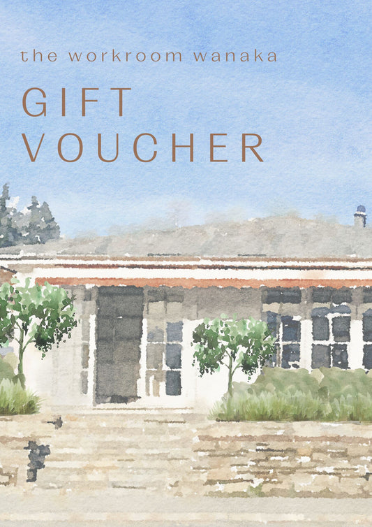 Gift voucher titled "THE WORKROOM ONLINE DIGITAL GIFT VOUCHER" from The Workroom NZ, adorned with a watercolor illustration of a building with a red roof amidst lush greenery and delicate floral accents, featuring the text "the workroom wanaka GIFT VOUCHER" at the top.