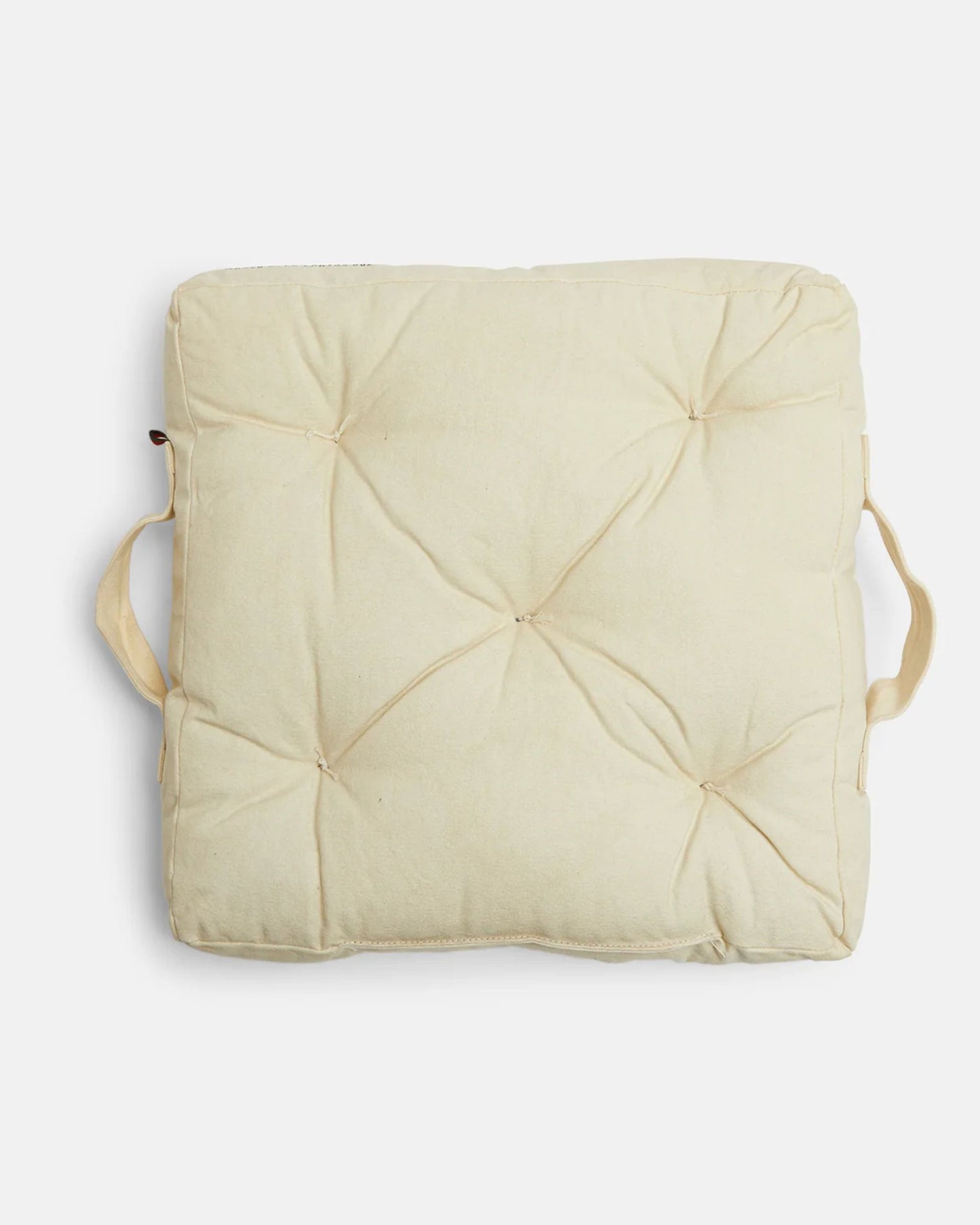 The CAMP FIRE OUTDOOR FLOOR CUSHION - ANGORA by Pony Rider, featuring a square, beige design with tufted buttons and two side handles, is showcased on a white background—ideal for outdoor adventures.