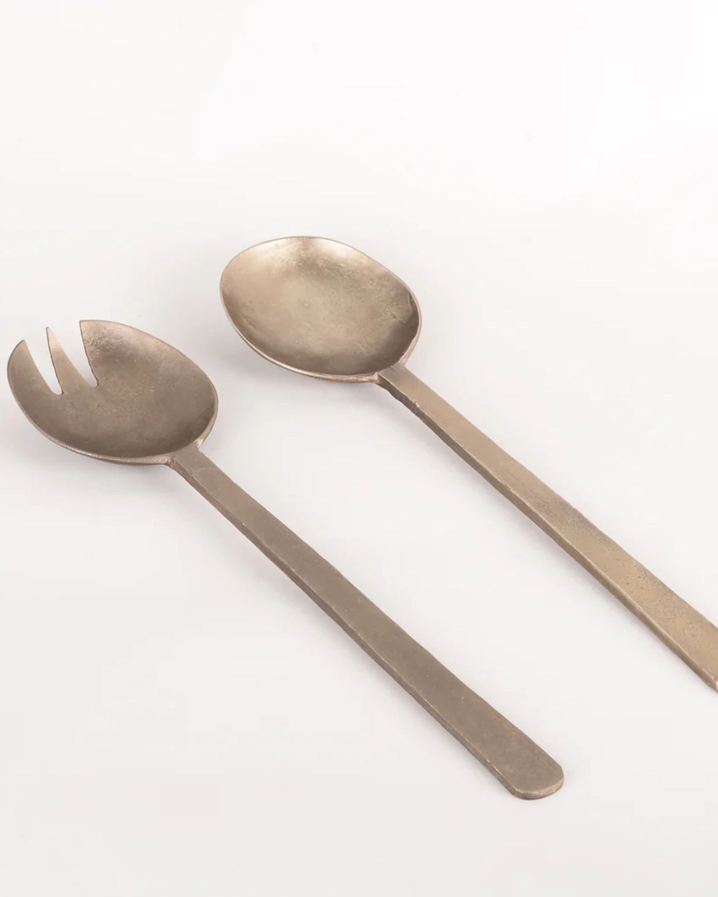 Two antique flat handle serving utensils, from New Direction's ANTIQUE FLAT HANDLE SERVING SPOONS collection, rest on a white background. One is a fork and the other is a spoon; both feature long handles and have a matte finish.