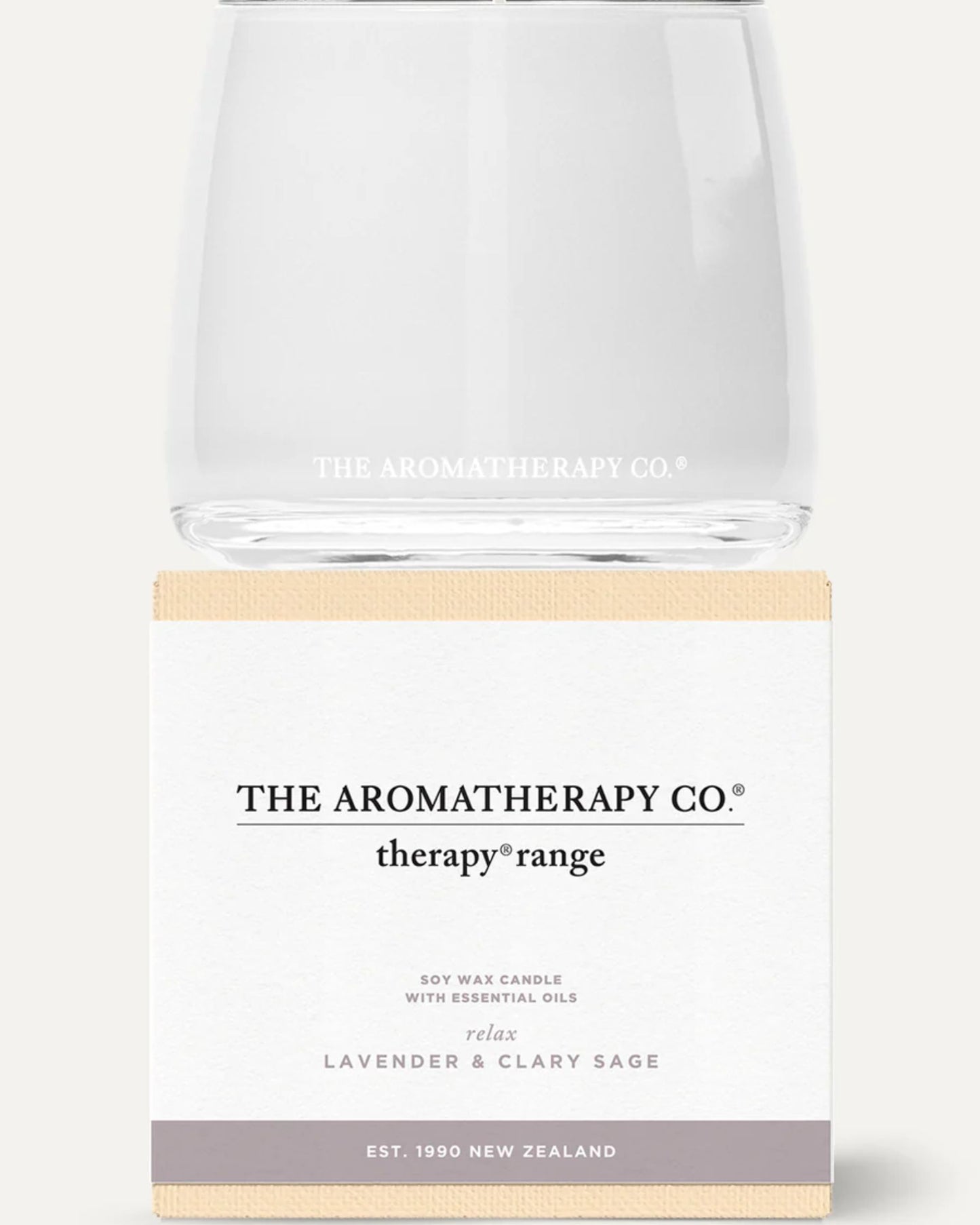 A glass candle holder displaying the The Aromatherapy Co logo is positioned above a beige and white box labeled "Therapy Range." This soy wax candle, crafted by Aromatherapy Candles since 1990 in New Zealand, offers relaxation with its lavender and clary sage scent through the infusion of essential oils.