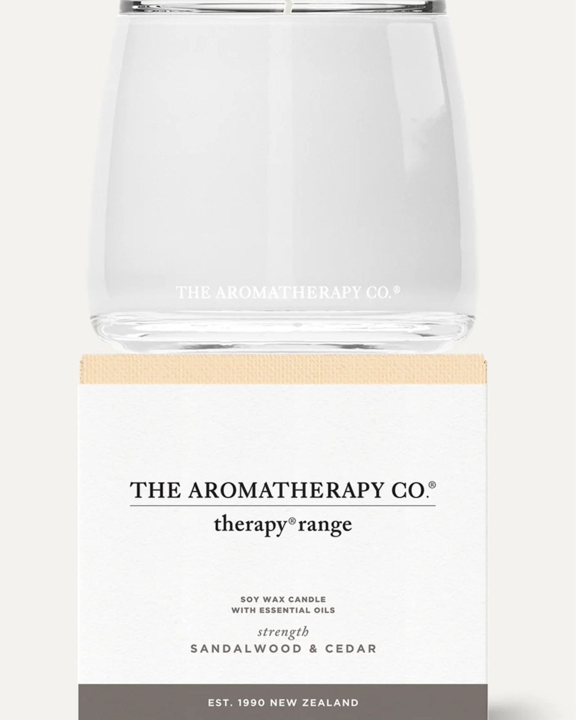 A clear glass container holds the AROMATHERAPY CANDLE from The Aromatherapy Co's therapy range, infused with sandalwood and cedar essential oils. Proudly crafted in New Zealand since 1990, this candle promises a serene and soothing aromatic experience.