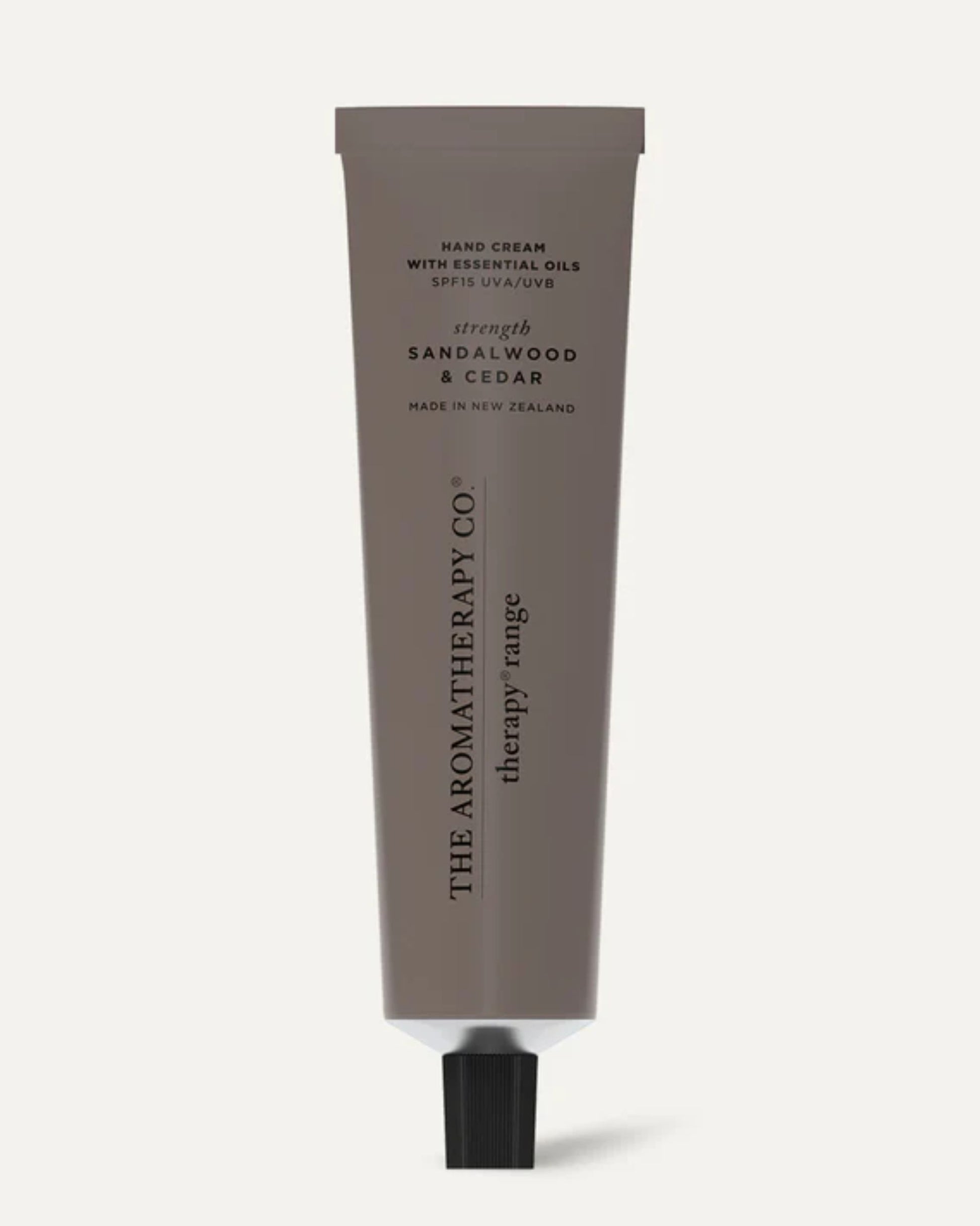 A brown tube of AROMATHERAPY HAND CREAM from The Aromatherapy Co. features sandalwood and cedar essential oils, provides SPF 15 protection, and is made in New Zealand. The packaging is completed with a sleek black screw cap.