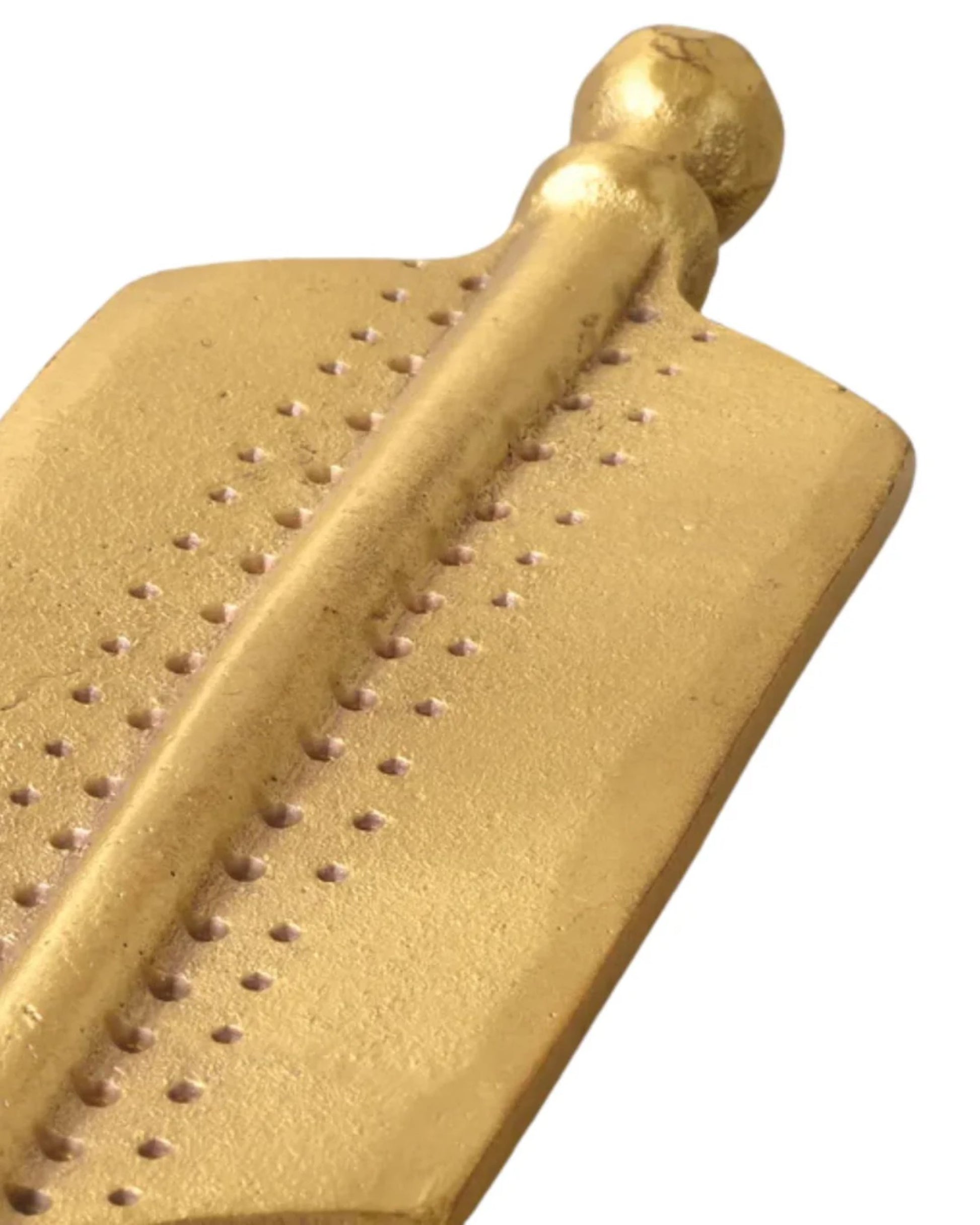 A close-up of the ARROW BRASS HOOK by New Direction showcases a stylish accessory, featuring intricate dot patterns on its gold-colored surface that highlight the texture and shine of the material.