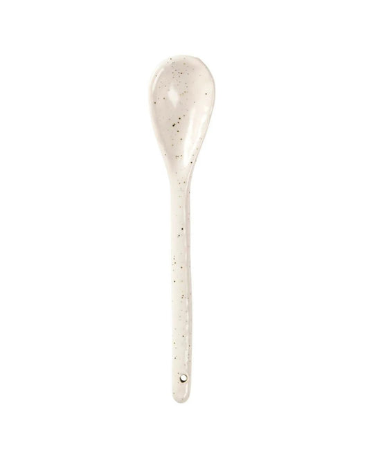The Broste CERAMIC TEASPOON is a speckled cream-colored utensil featuring a long handle and rounded bowl, ideal for tea and coffee enthusiasts. Its design includes a small hole at the end for convenient hanging within your kitchen collection, all set against a white background.