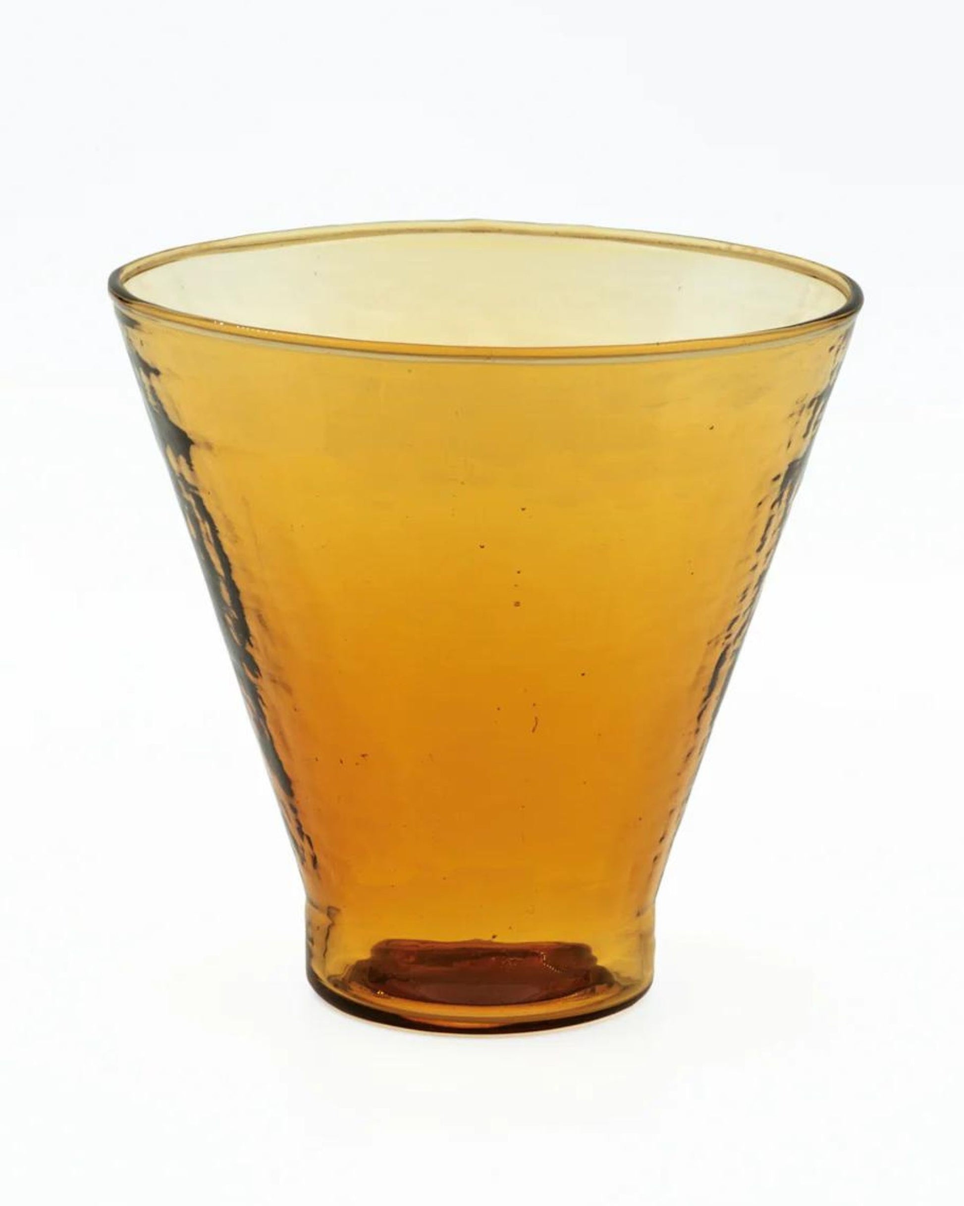 A COCKTAIL / WINE GLASS by Bianca Lorenne, characterized by its brown, transparent, conical shape and slightly textured surface with an organic hammered finish made from recycled glass, set against a plain white background.