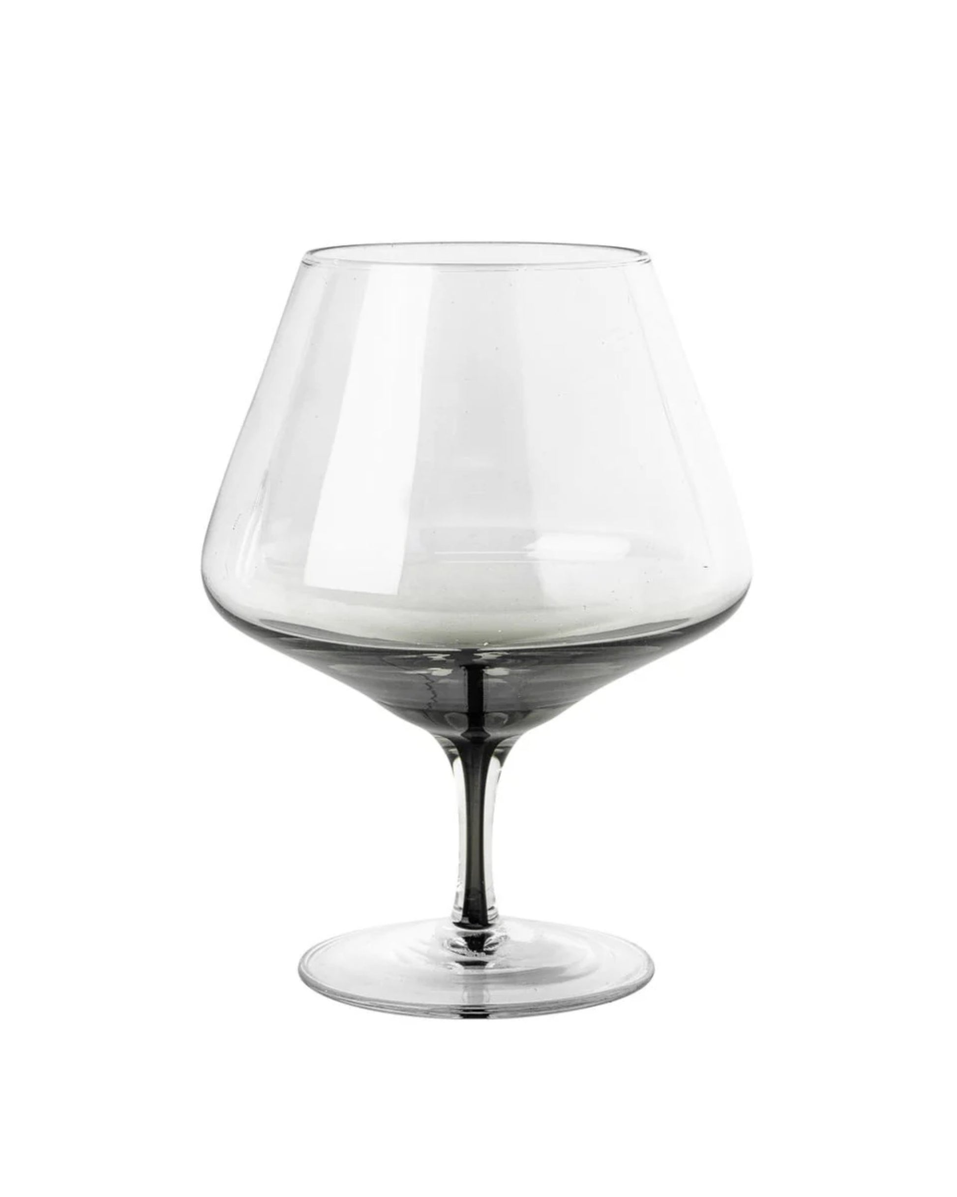 A clear, empty COGNAC GLASS with a wide bowl and short stem, reflecting Scandinavian simplicity, set against a plain white background—an elegant piece from the Broste collection.