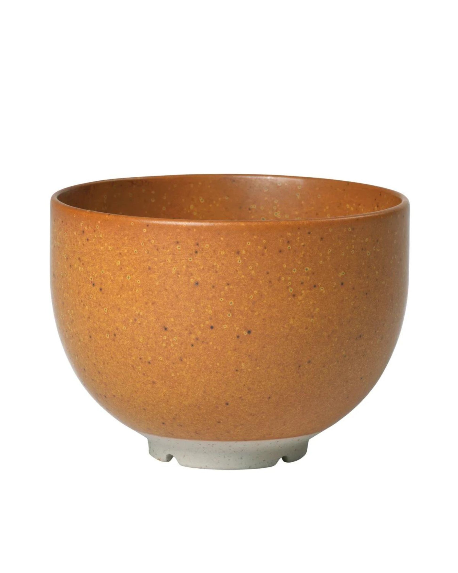 The ELI BOWL - CARAMEL BROWN by Broste is elegantly showcased against a plain white background. This ceramic bowl features a smooth, speckled surface reminiscent of Japanese tableware. It has a round shape with a slightly outward-curving rim and rests on a small, unglazed base that highlights its refined design.