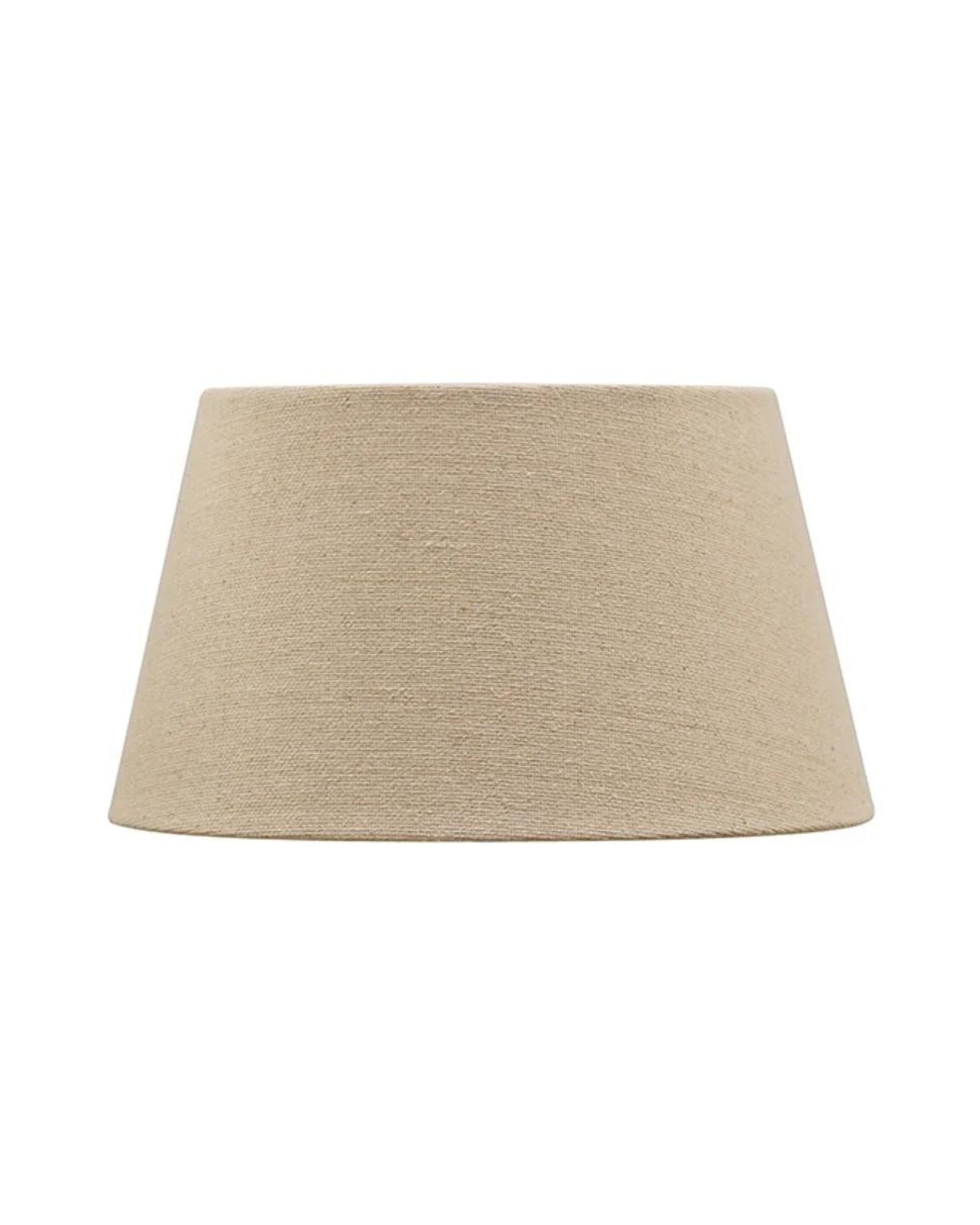 The FLAX BASKET WEAVE TAPERED DRUM 31CM LAMPSHADE by CC interiors is a beige fabric lampshade with a simple, cylindrical shape crafted from linen, set against a plain white background.