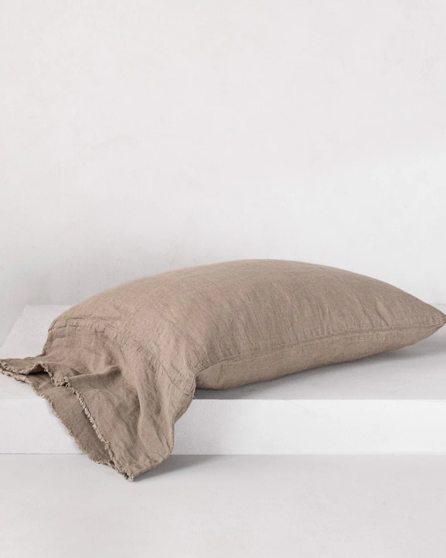 A HALE FLOCCA FLOPPY END PILLOWCASE by Hale Mercantile Co in linen beige, featuring Flocca hand-tufted edges, rests on a white surface against a light gray background.