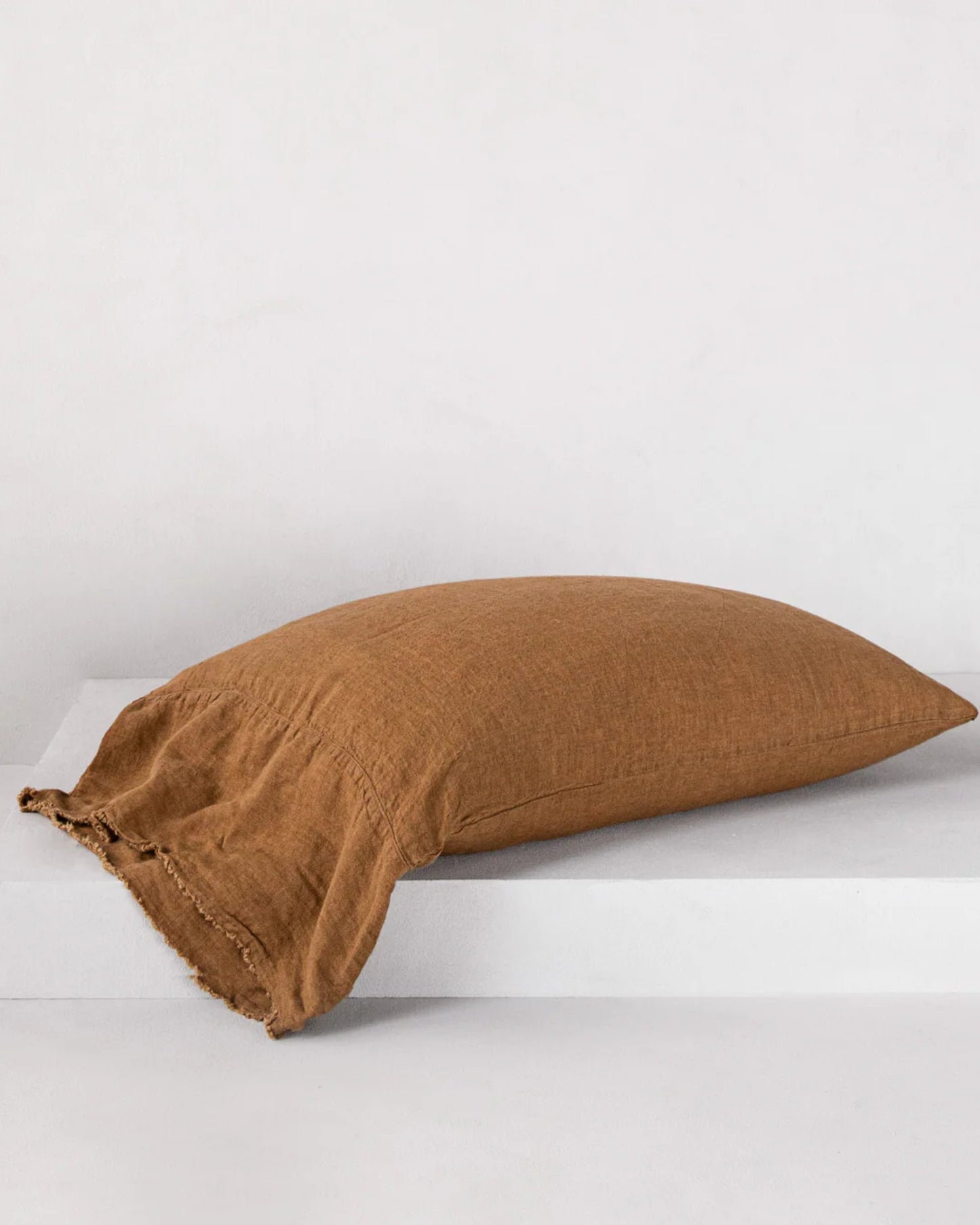 The HALE FLOCCA FLOPPY END PILLOWCASE by Hale Mercantile Co, featuring Flocca hand-tufted edges and crafted from pure linen bedding in a brown hue, is elegantly displayed on a white surface against a plain background.