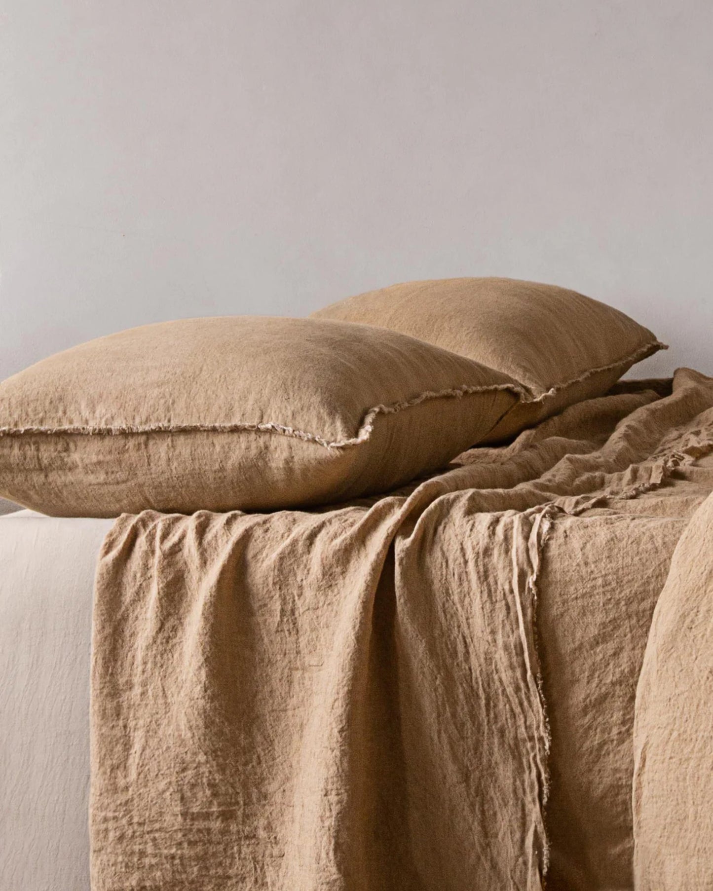 Arranged on a bed against a plain white background are two HALE STANDARD FLOCCA PILLOWCASES in beige and a matching blanket, all showcasing a textured, rustic appearance. The handcrafted quality of the pillowcases by Hale Mercantile Co enhances the soft, cozy feel, creating a warm and inviting atmosphere.