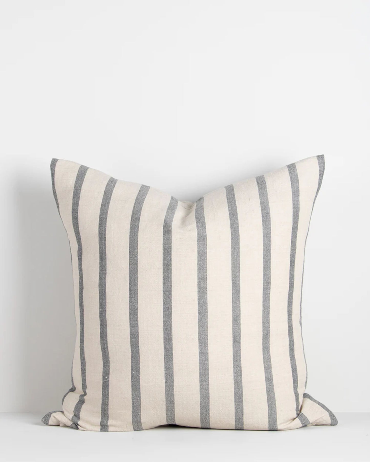 The Baya HAMPTON CUSHION boasts a casual stripe design characterized by a cream background adorned with vertical gray stripes and is crafted from natural fibers, set on a plain white backdrop.