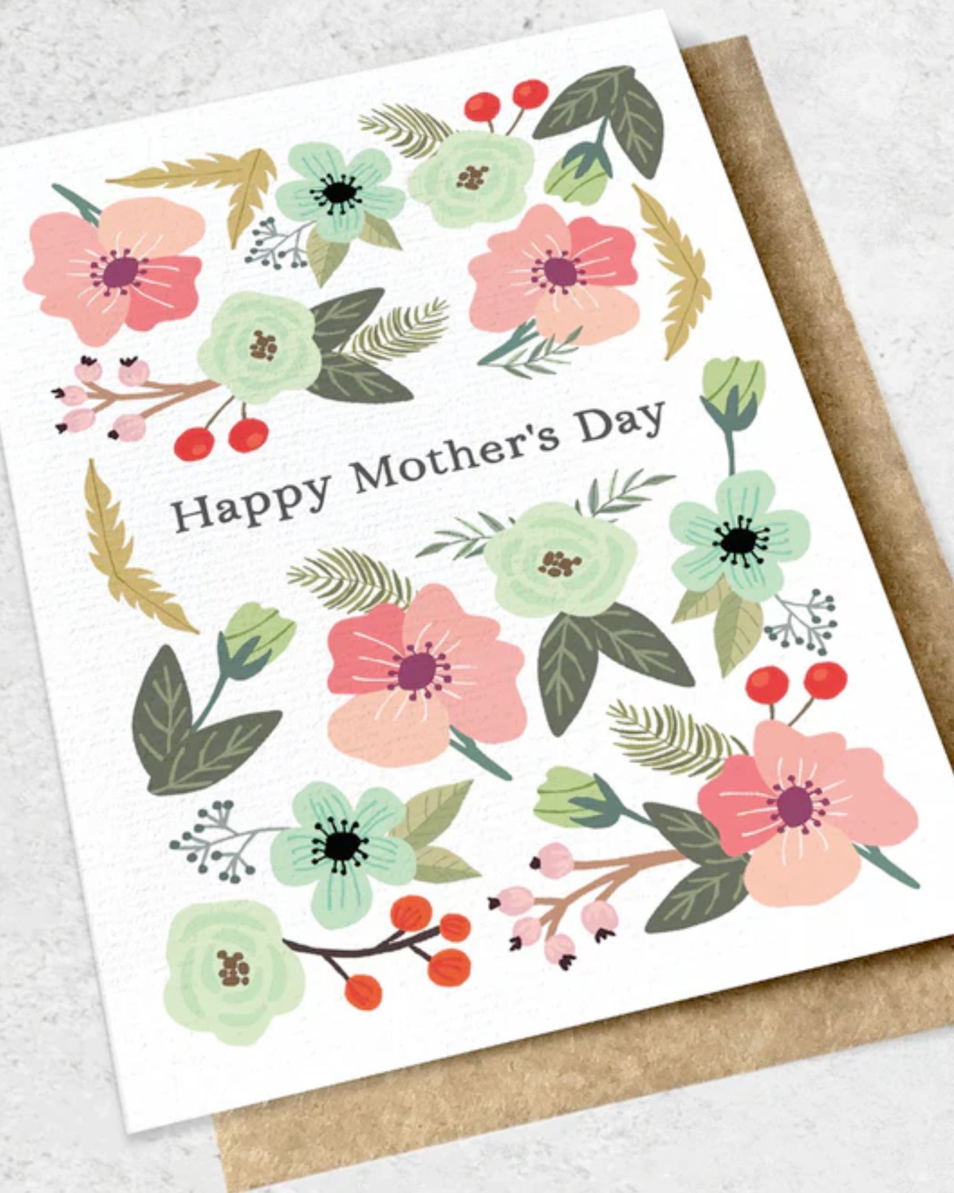 The "HAPPY MOTHER'S DAY - GREETING CARD" by Ink Bomb features "Happy Mother's Day" text encircled by pastel-colored flowers and lush green leaves on a white background, beautifully presented in a premium textured kraft envelope.