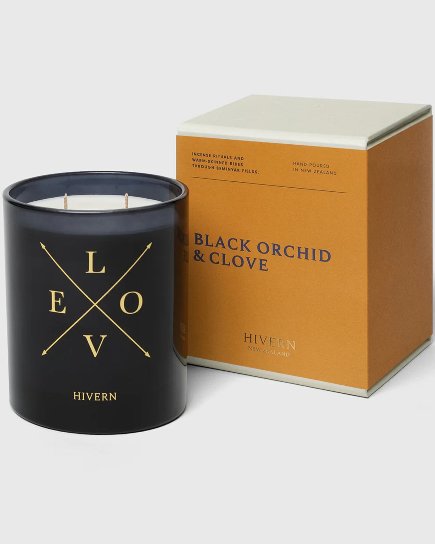 A black HIVERN CANDLE, inscribed with the word "LOVE," sits next to a gold and white box labeled BLACK ORCHID & CLOVE, showcasing New Zealand's exquisite Hivern home fragrance. With a burn-time of 55 hours, this elegant duo is beautifully presented on a white background.