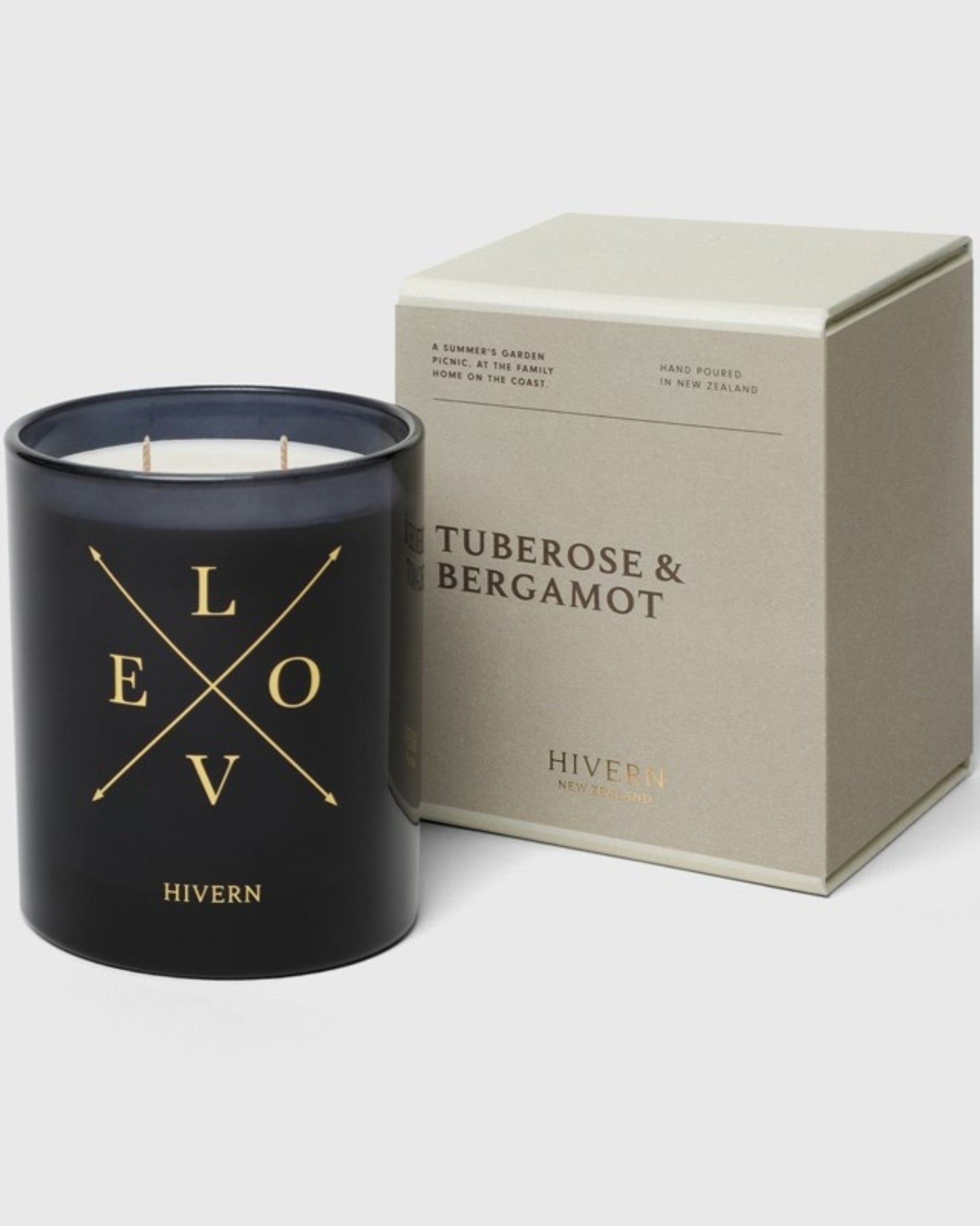 A black HIVERN CANDLE, adorned with gold letters spelling Hivern, is displayed next to a beige box labeled Tuberose & Bergamot, proudly indicating its origin: Hand poured in New Zealand. This fragrant home accessory includes three wicks and offers a burn time of 55 hours.