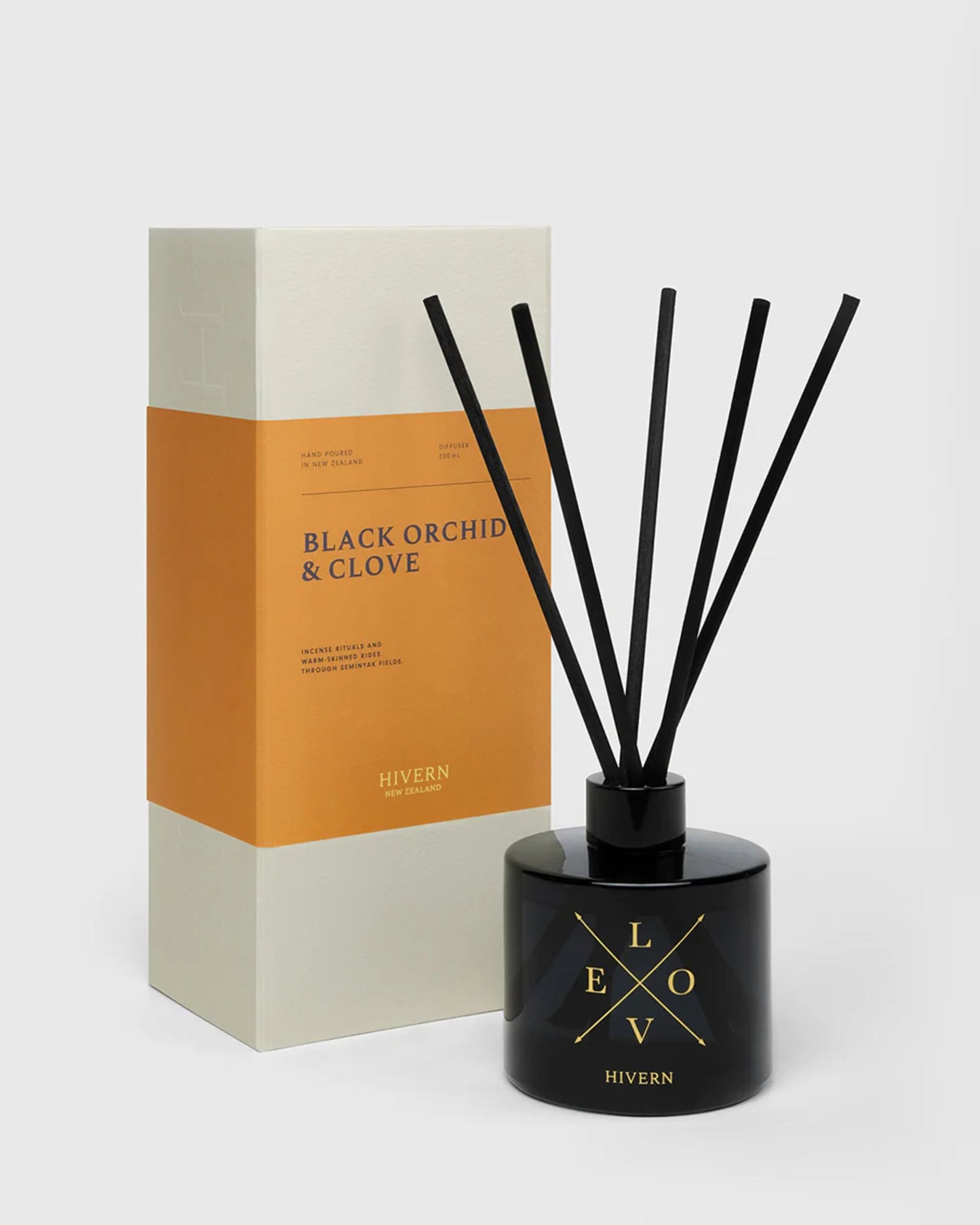 The HIVERN DIFFUSER from Hivern showcases an elegant dark bottle paired with silk fibre reeds, labeled Black Orchid & Clove. It comes in a coordinated beige and orange box, perfectly designed for optimal scent dispersion.