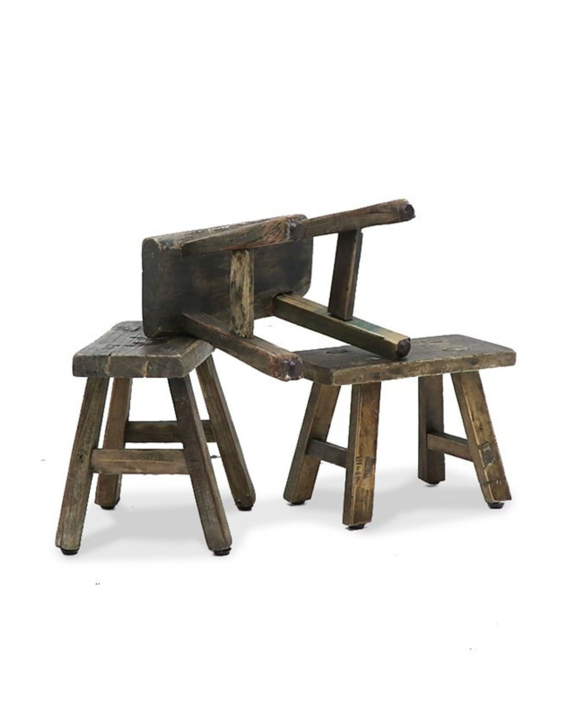 The MINI STOOL by Hawthorne, crafted from reclaimed elm wood, is depicted in a trio against a plain white backdrop. Two stools stand upright while one rests overturned, all of them embodying a weathered vintage aesthetic that highlights an eco-conscious choice in rustic decor.