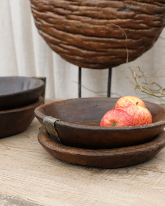 Hawthorne's ORIGINAL WOODEN PARAT on a wooden surface, elegantly holding three red apples, with a textured brown decorative element enhancing the composition. This handmade piece from India demonstrates that styles may vary, adding cultural depth to your decor.