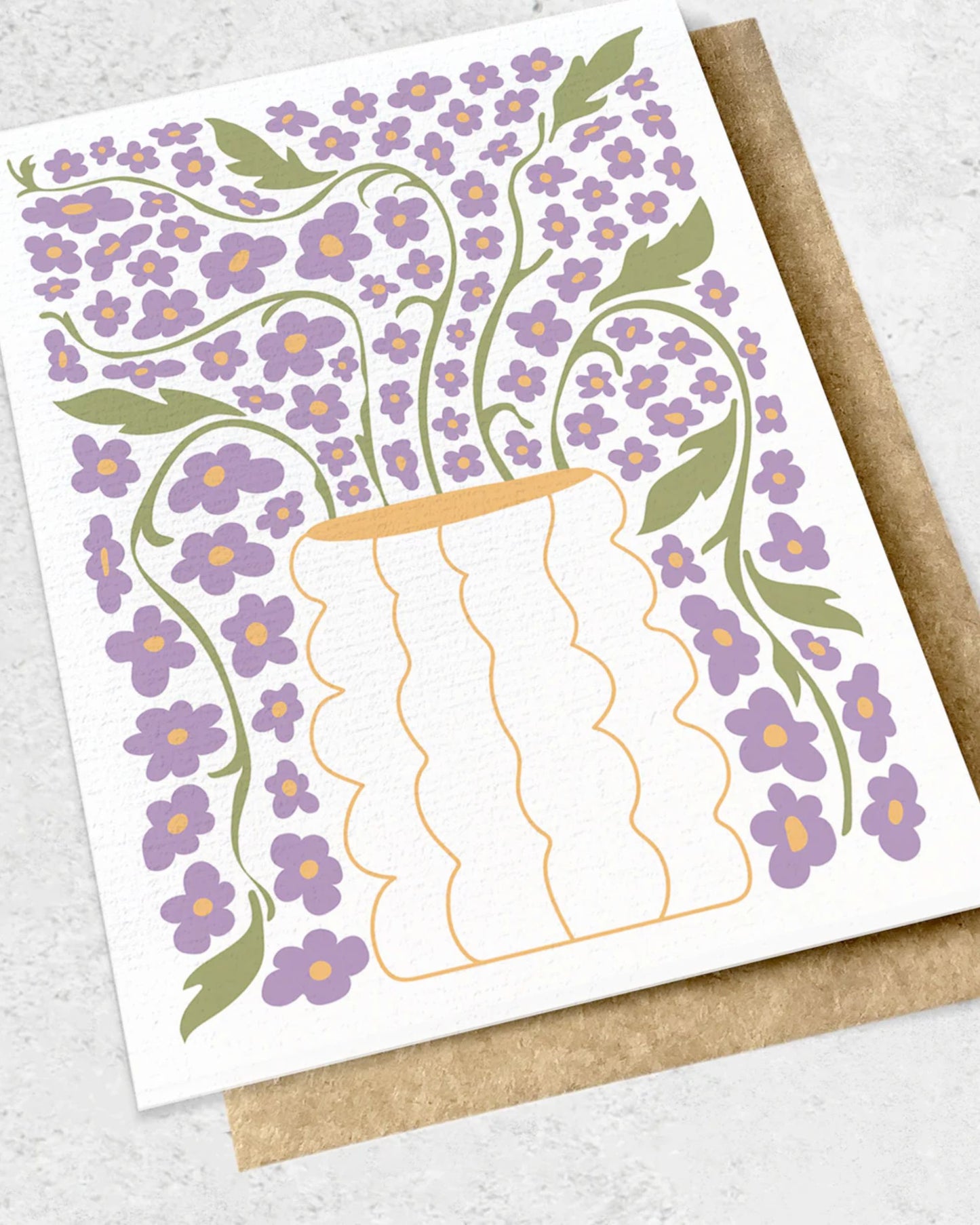 The PURPLE ABSTRACT - GREETING CARD by Ink Bomb showcases a whimsical illustration of a vase filled with purple flowers and green leaves on a premium textured card, accompanied by a brown kraft envelope.