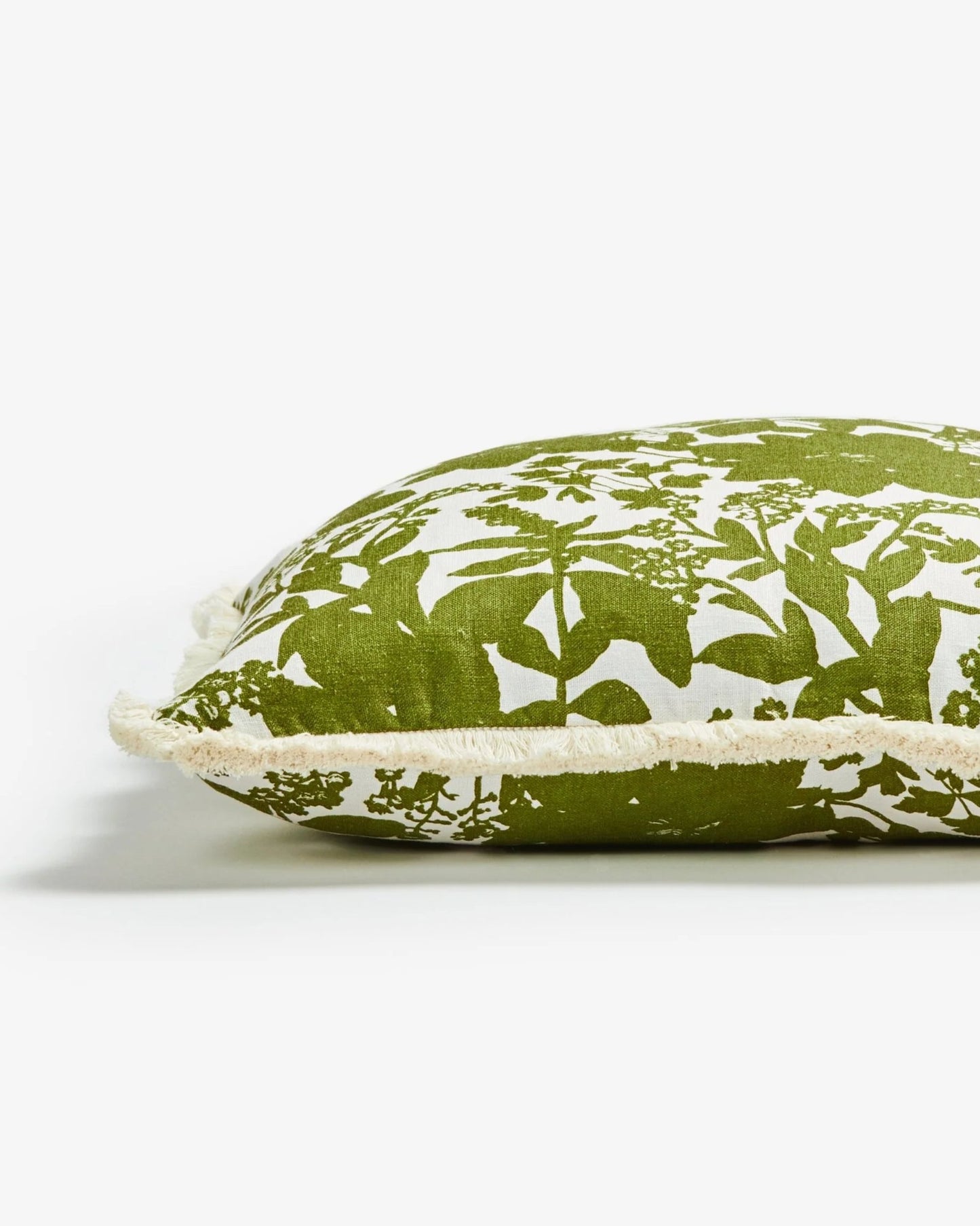 The HERB REVERSE KHAKI pillow by Bonnie and Neil, measuring 50cm x 50cm, features a green and white floral pattern reminiscent of a botanical tapestry. The rectangular pillow with fringed edges is showcased in side view against a plain white background.