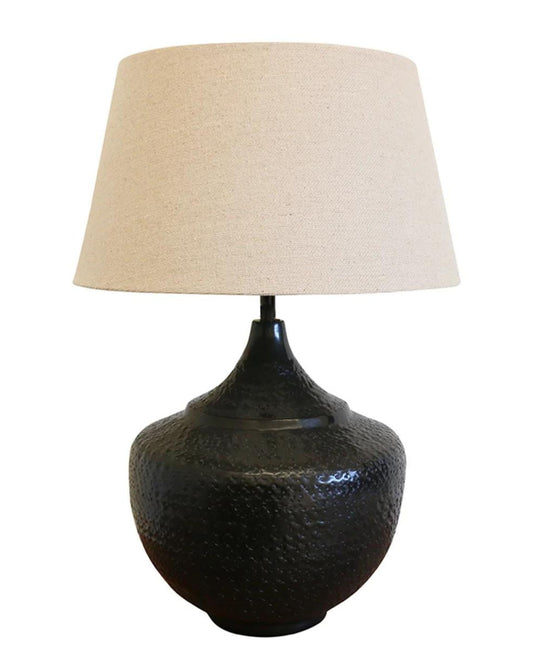 Introducing a modern silhouette table lamp by CC interiors, featuring the Sarajavo Lamp Base in a Black/Bronze Finish. This elegant design combines a textured black ceramic base with a beige fabric lampshade, making it a perfect addition to any home decor.